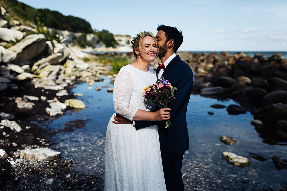 groom kissing bride, natural wedding photos in Stevns Klint, Denmark. Photos by Natalia Cury