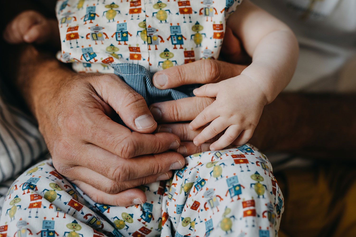 Chubby baby hands delicately resting on top of parent's hand during an intimate baby photoshoot in Copenhagen