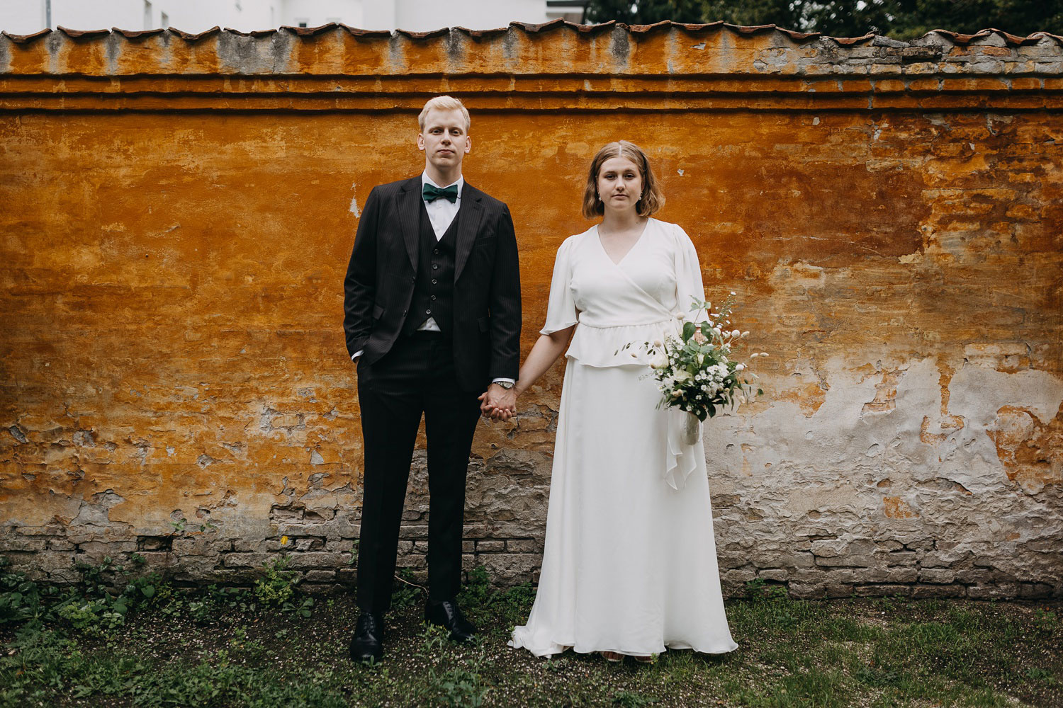 Elegant bride and groom standing holding hands at Frederiksberg Gardens in Copenhagen