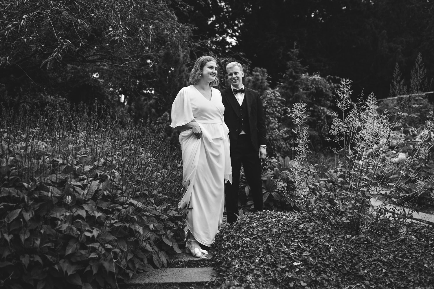 black and white wedding photo of newlyweds in formal attire, radiating joy in the stunning Frederiksberg Have gardens