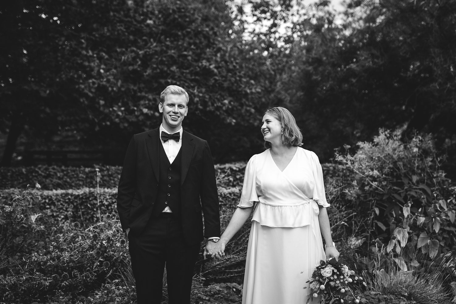 Elegant bride and groom standing holding hands at Frederiksberg Gardens in Copenhagen