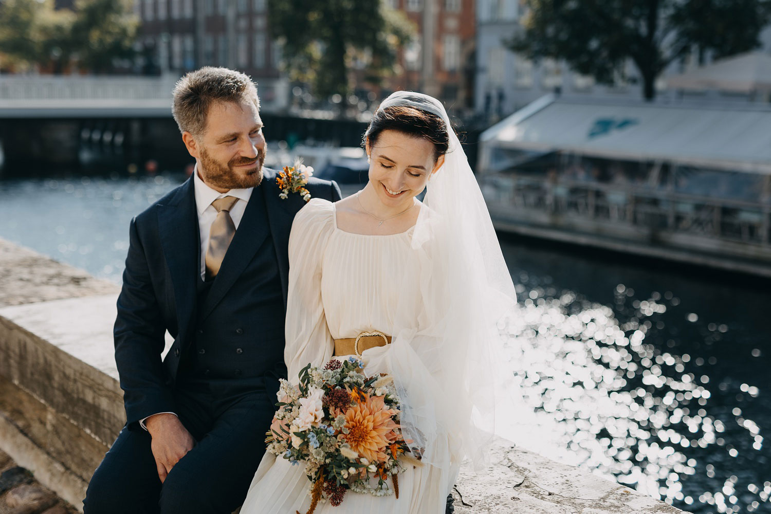 bride and groom sitting by Frederiksborg Kanal in Copenhagen