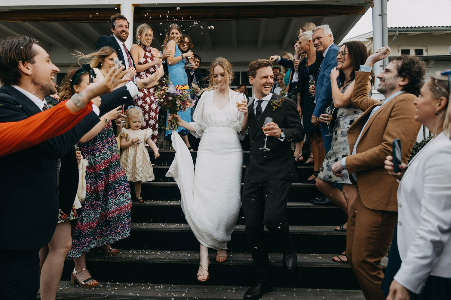 A shower of rice cascades down as the newlyweds gracefully descend the stairs at Helenekilde Badehotel