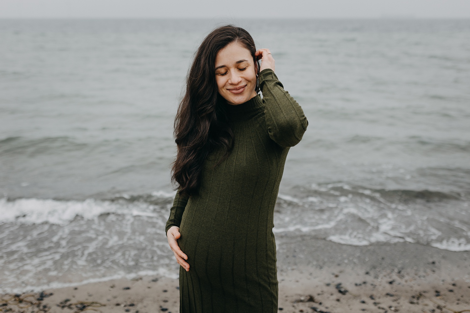 Pregnant woman posing on Amager Strand beach with ocean in background