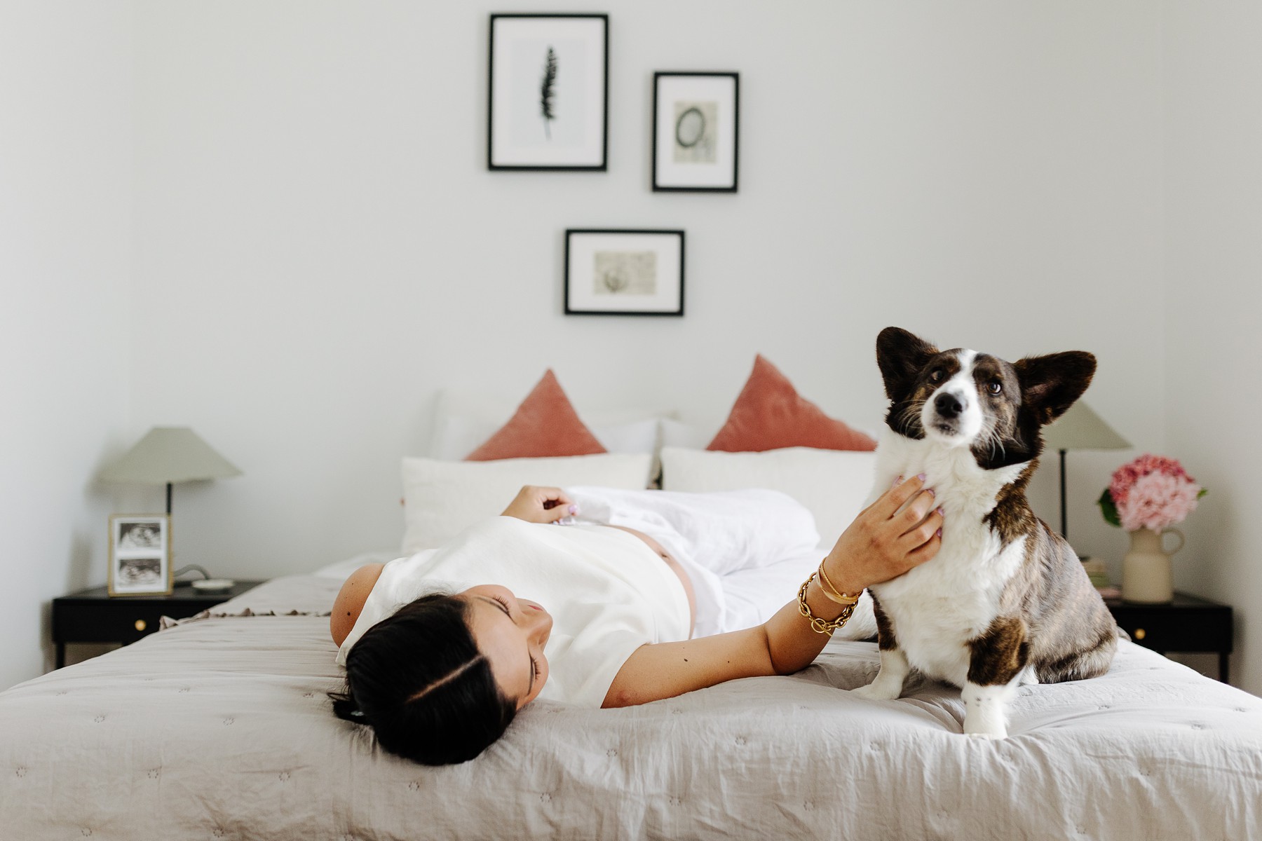 Intimate lifestyle maternity photo of a mom-to-be snuggling her dog while resting on the bed
