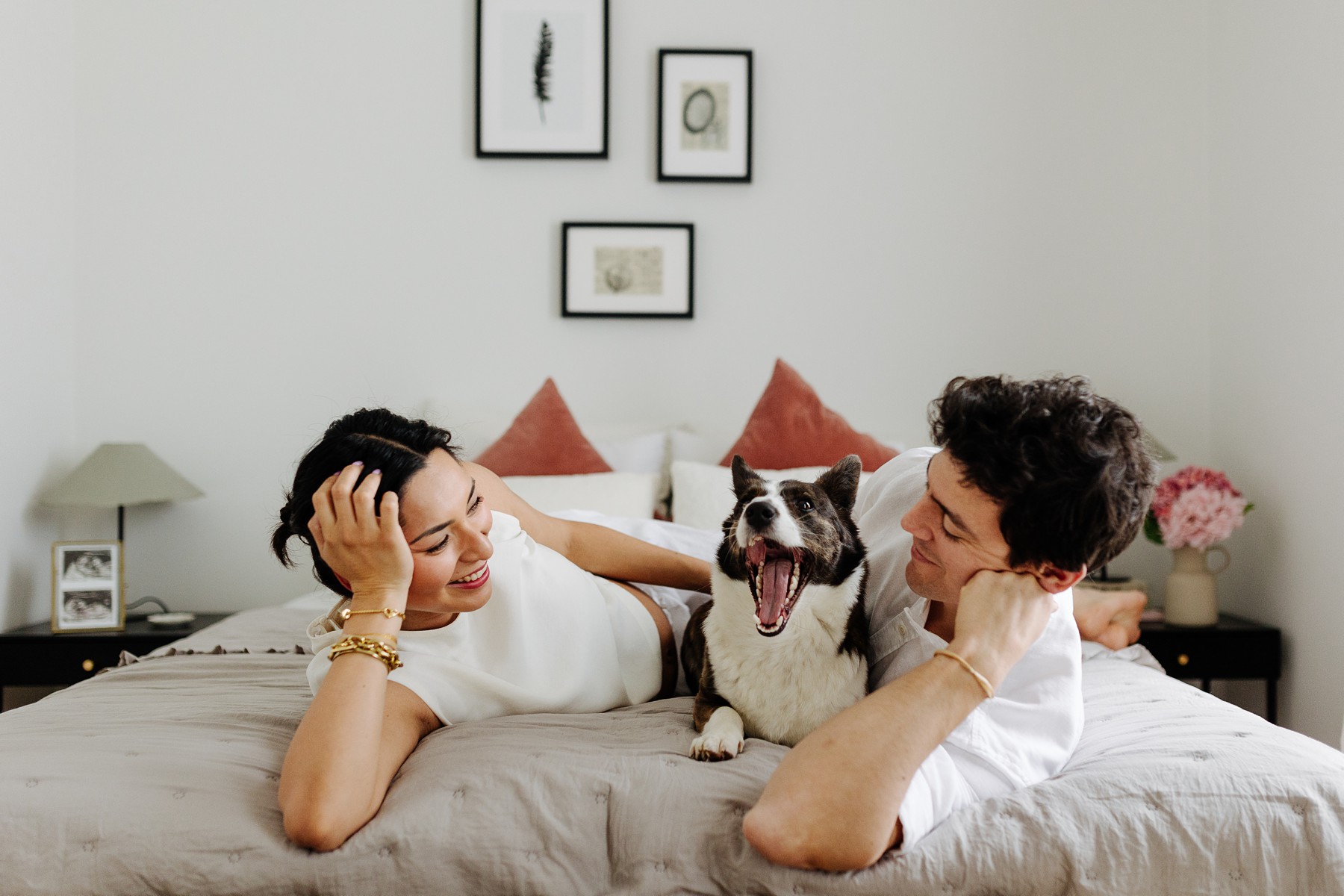 Lifestyle maternity photoshoot at home in Copenhagen with couple and their dog cuddling on the bed